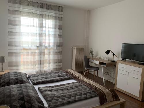 a bedroom with two beds and a desk and a television at Liliom Apartman Pécs in Pécs