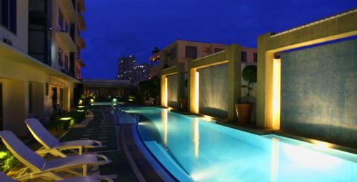 - une piscine avec des chaises longues à côté d'un bâtiment dans l'établissement Astoria Plaza, à Manille