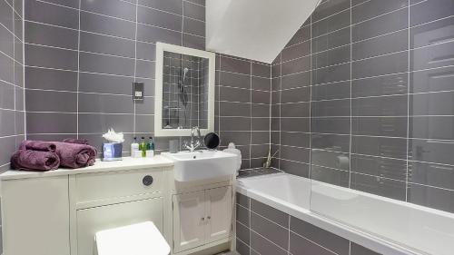 La salle de bains est pourvue d'un lavabo et d'une baignoire. dans l'établissement The King's- Gorgeous City Centre Apartment, à York