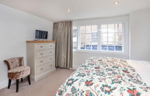 a bedroom with a bed and a chair and a window at The King's- Gorgeous City Centre Apartment in York