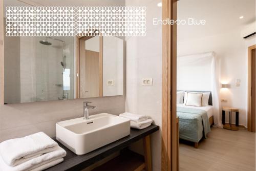 a bathroom with a sink and a mirror and a bed at Endless Blue in Palaiochóra