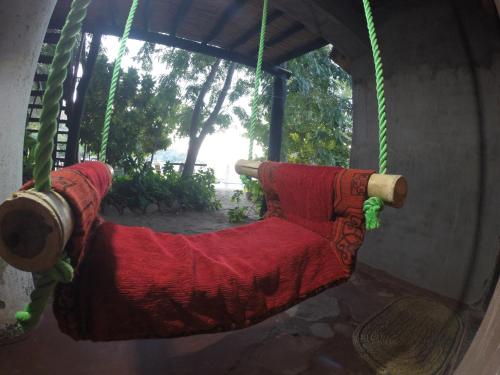 a red hammock hanging from a porch at Mufasa Eco Lodge in Monkey Bay