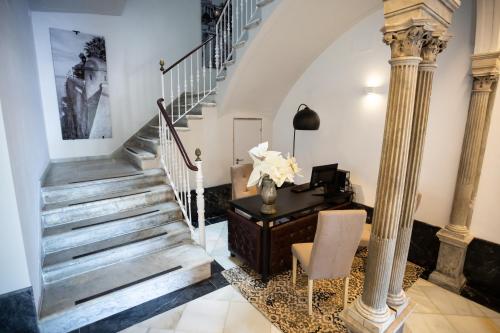 a staircase in a home with a desk and columns at Plazuela del Carbón Suites in Cádiz