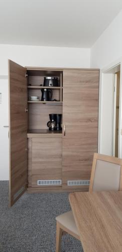 a cupboard in a room with a table and a chair at Gästehaus Rostock Lütten Klein in Rostock