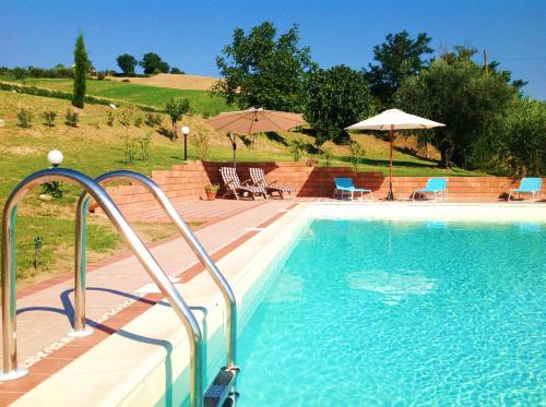 a large swimming pool with chairs and umbrellas next to at Casa Carolina Santa Maria in Montebello di Bertona