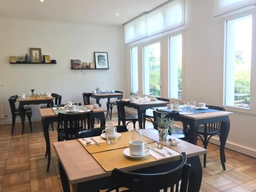 a dining room with tables and chairs and windows at Hotel de France in Saint-Pol-de-Léon