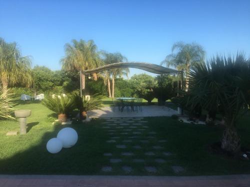 a garden with a patio with a table and trees at Feudogrande Bio Relais Hotel in Fiumefreddo di Sicilia