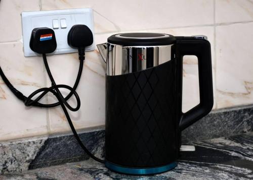 a black coffee pot on a counter next to a phone at Onimz Apartments in Abuja