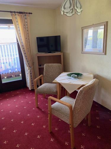 a room with a table and two chairs and a television at Pension Erna in Zwiesel