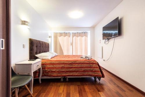 a bedroom with a bed and a desk and a television at El Triunfo Apartments in Cusco