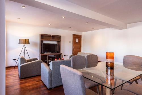 a living room with a glass table and chairs at El Triunfo Apartments in Cusco