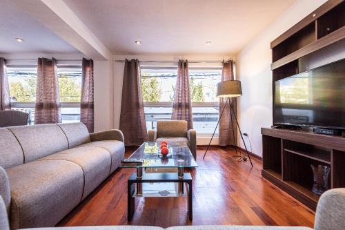 a living room with a couch and a flat screen tv at El Triunfo Apartments in Cusco
