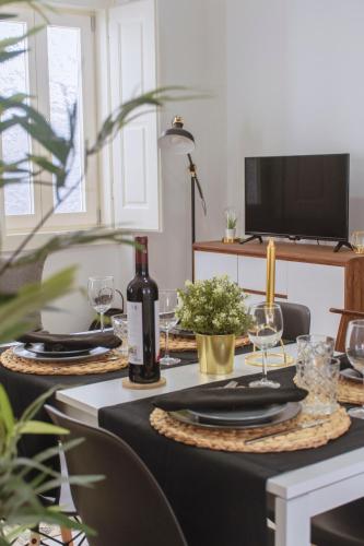 a table with a bottle of wine and glasses on it at Living Coimbra Corpo de Deus in Coimbra
