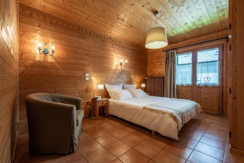 une chambre avec un lit et une chaise dans une pièce dans l'établissement Le BOUQUETIN, aux Gets