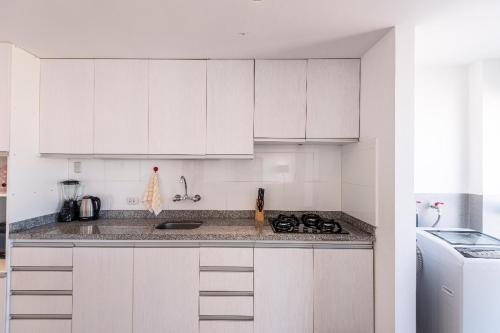 a kitchen with white cabinets and a stove top oven at El Triunfo Apartments in Cusco