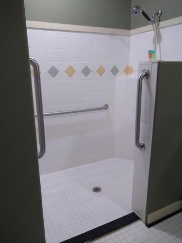 a bathroom with a shower with a toilet and a tile floor at Southern Comfort Suites in Mayfield