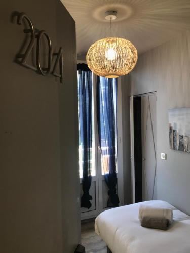 a bedroom with a bed and a chandelier and a window at Hotel La Calanque in Mandelieu-la-Napoule
