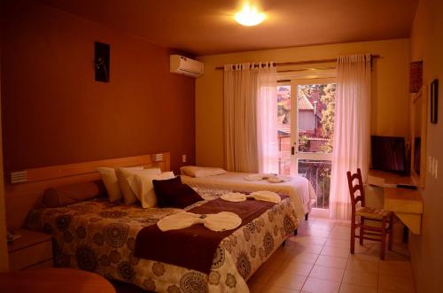 a hotel room with two beds and a window at Pousada Tango in Gramado