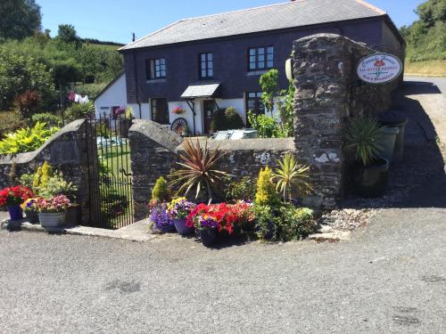 a house with flowers in front of a fence at Coombe House B&B in Cawsand