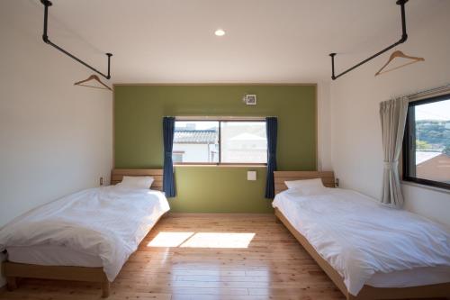 a bedroom with two beds and a window at Shioya Hostel in Akune
