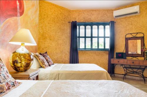 a bedroom with two beds and a window at Hacienda Boutique B&B and Spa Solo Adultos in Cozumel
