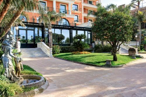 a building with palm trees and a walkway at Grand Hotel Royal in Sorrento