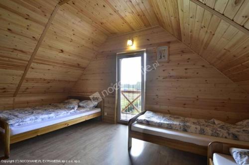 two beds in a log cabin with a window at Sosenka 6 - całoroczne domki rekreacyjne in Milicz
