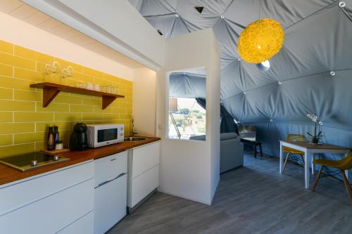 a kitchen with yellow and white cabinets and a table at wecamp Reserva Alecrim in Santiago do Cacém