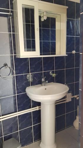 a blue tiled bathroom with a sink and a mirror at Apartmani Lazarevic in Luštica