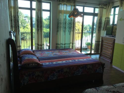 a bedroom with a bed and a balcony with windows at Le Bamboo Guesthouse in Mahébourg