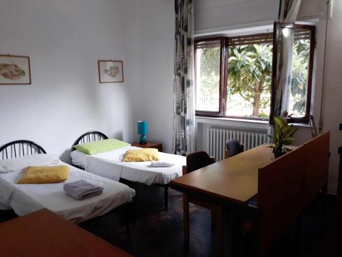 シエナにあるBed in Sienaのベッド2台、テーブル、窓が備わる客室です。