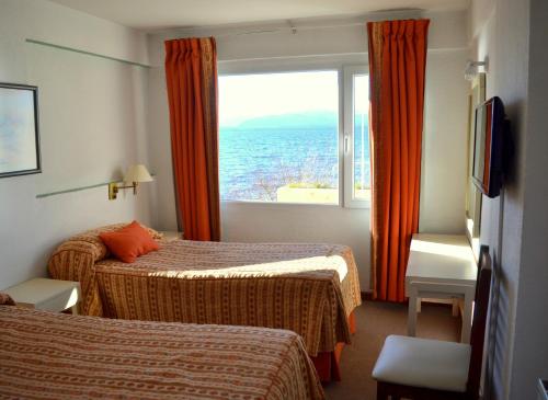 een hotelkamer met twee bedden en een groot raam bij Hotel Bariloche Flat in Bariloche