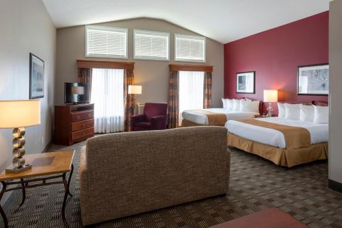 een hotelkamer met 2 bedden en een bank bij GrandStay Hotel & Suites Ames in Ames