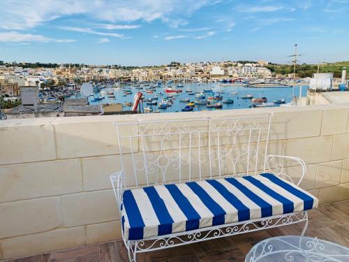 a bench on a balcony with a view of a harbor at Anthony's Sea Stay in Marsaxlokk