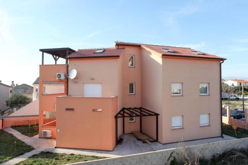 a large pink building with a rooftop at MILKA APARTMANI POVLJANA in Povljana