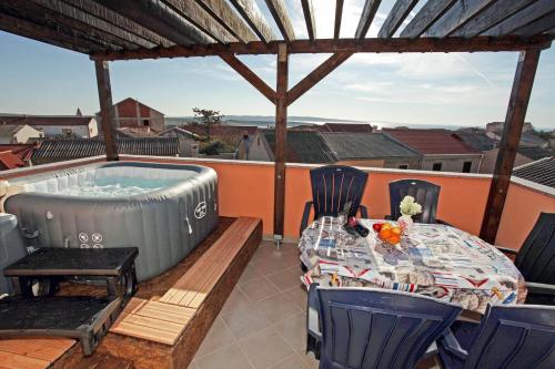 a patio with a table and a hot tub at MILKA APARTMANI POVLJANA in Povljana