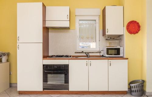 a kitchen with white cabinets and a microwave at MILKA APARTMANI POVLJANA in Povljana