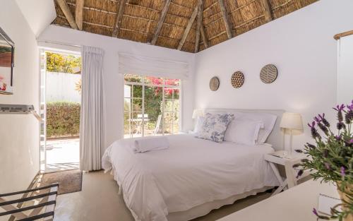 a white bedroom with a bed and a window at Green Park Manor in Johannesburg