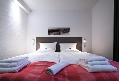 Una cama con sábanas blancas y toallas. en dat geele hus Nr. 3, en Büsum