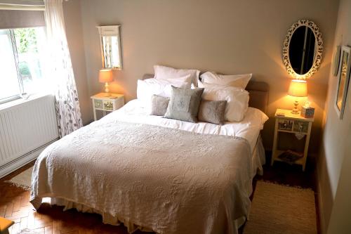 um quarto com uma cama branca com almofadas e um espelho em Mortimer Trail B and B em Aymestrey