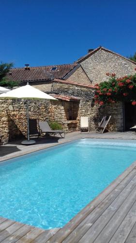 une piscine devant un bâtiment en pierre dans l'établissement Les Buis, à Castelnaud-la-Chapelle