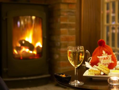 a table with a glass of wine next to a fireplace at Crown Spa Hotel Scarborough by Compass Hospitality in Scarborough