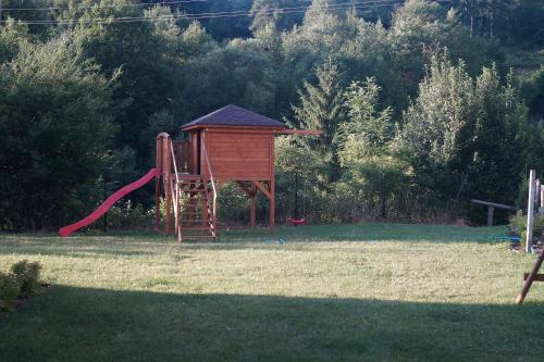 un parque infantil con un tobogán rojo y una estructura de juegos en Apartament Homole E2 Szczawnica en Szczawnica