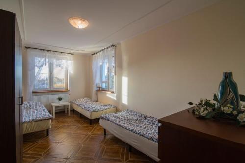 a room with two beds and two windows at PIONOW Rodzinne Apartamenty Urocza 10 in Krynica Morska