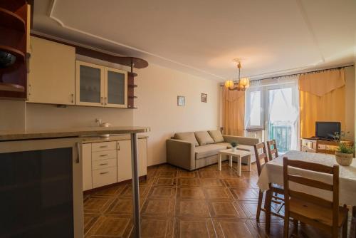 a kitchen and living room with a table and a couch at PIONOW Rodzinne Apartamenty Urocza 10 in Krynica Morska