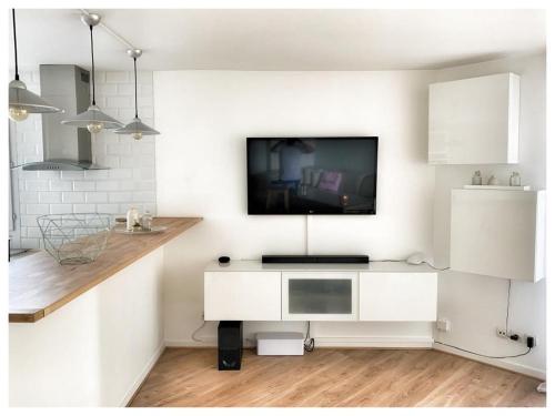 a white living room with a tv on a wall at Modern & Chic Appartement- GoodVibes Paris in Gonesse