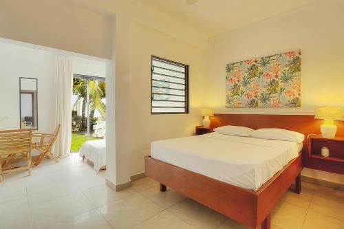 a bedroom with a large bed and a dining room at Auberge SeaFever in Mahébourg