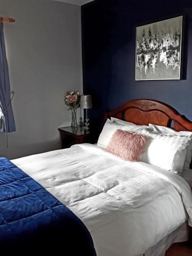 a bedroom with a white bed and a blue wall at Lake Avenue House in Ballyconnell