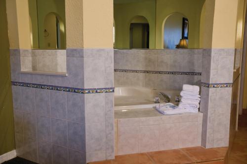 a bathroom with a tub and a sink with a mirror at Club Wyndham Sea Gardens in Pompano Beach