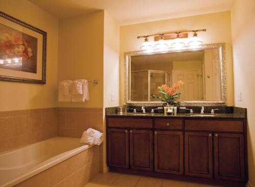 ein Badezimmer mit einem Waschbecken, einer Badewanne und einem Spiegel in der Unterkunft WorldMark Reunion in Kissimmee